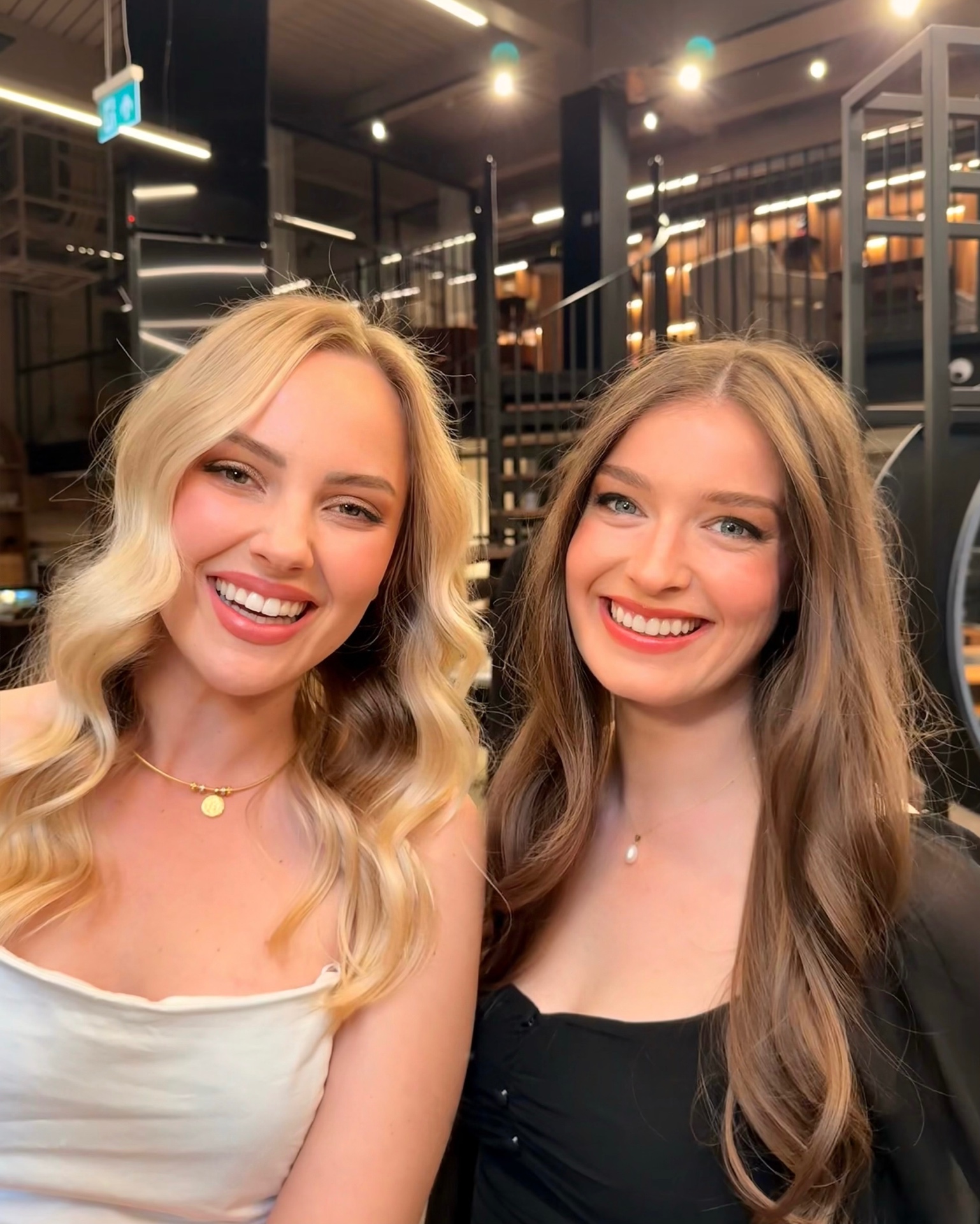 Two happy clients with glamorous soft-wave hair and glowing event makeup