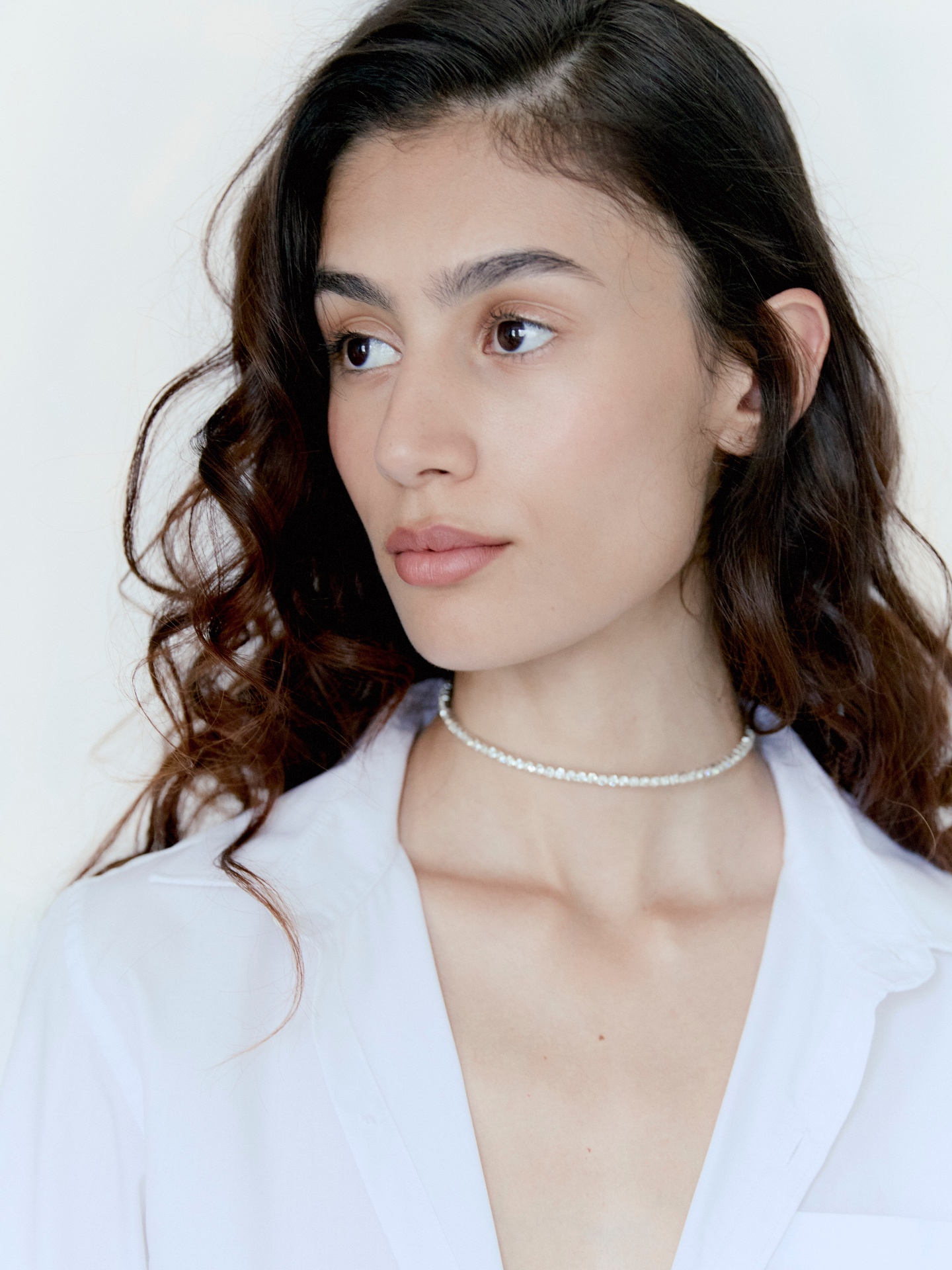 Soft glam beauty portrait with glowing skin, wavy hair and a delicate pearl choker