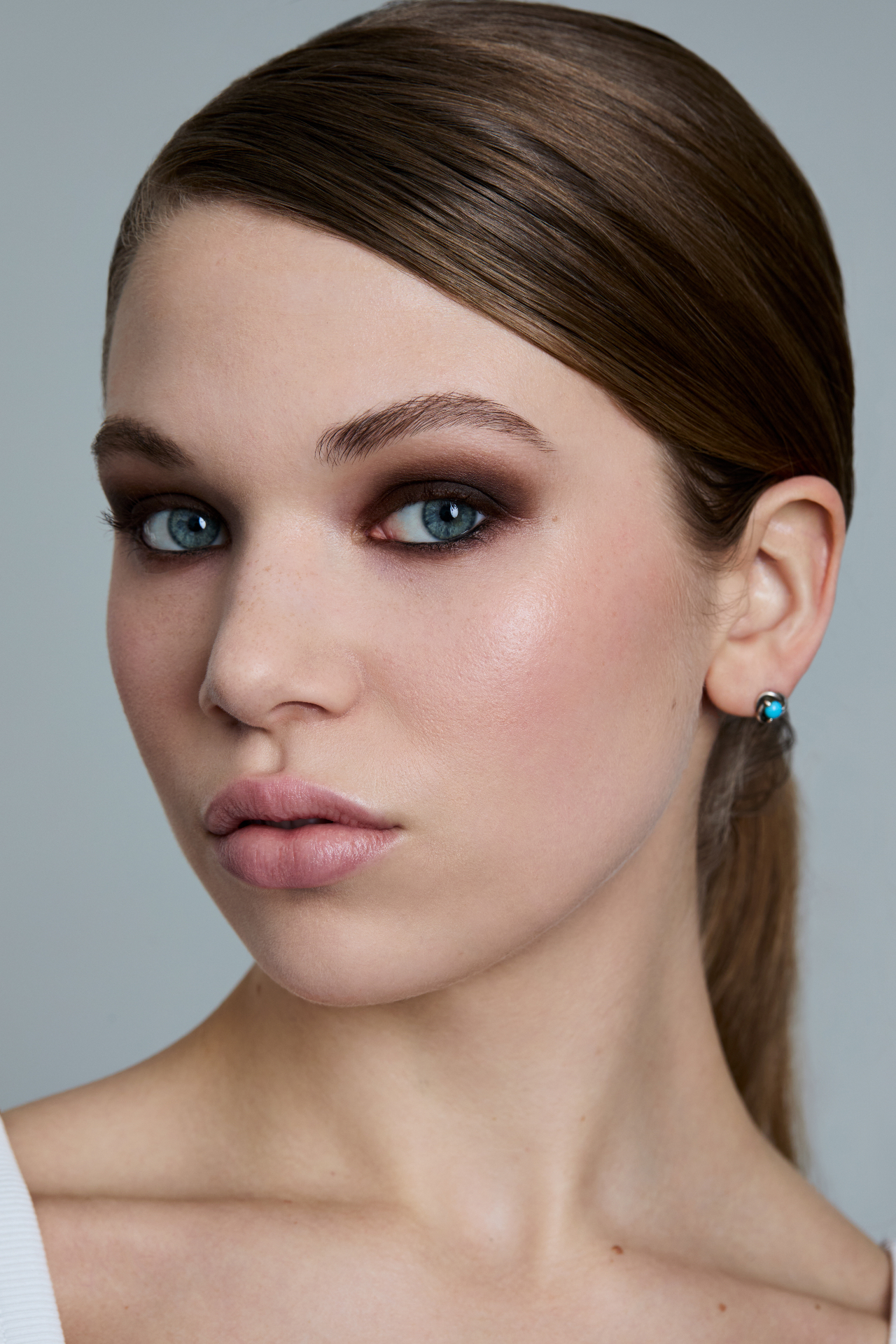 Natural beauty portrait with soft brown smoky eyes, glowing skin and a sleek low ponytail